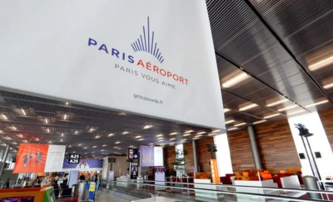 Zone d'enregistrement à l'aéroport de Paris avec comptoirs et écrans.