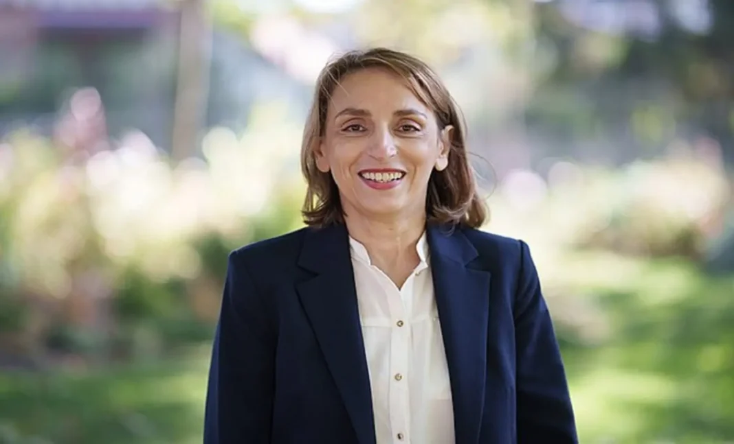 Députée d'origine algérienne en campagne Femme politique souriante en extérieur, portrait professionnel.