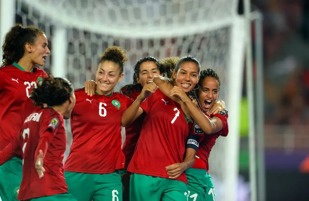 Joueuses marocaines de football célébrant un but lors d'un match.