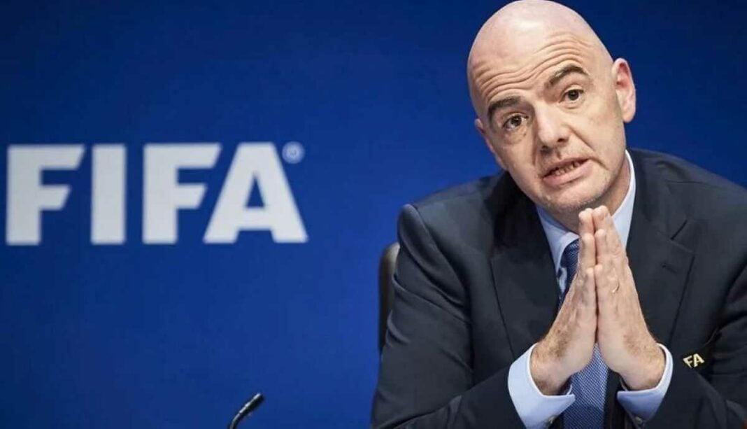 Président de la FIFA en conférence, gestuelle sérieuse.