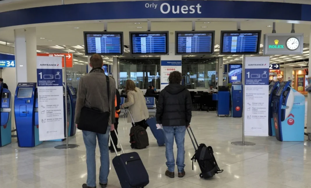 comptoirs d'enregistrement Voyageurs à l'aéroport d'Orly avec valises et écrans d'information.