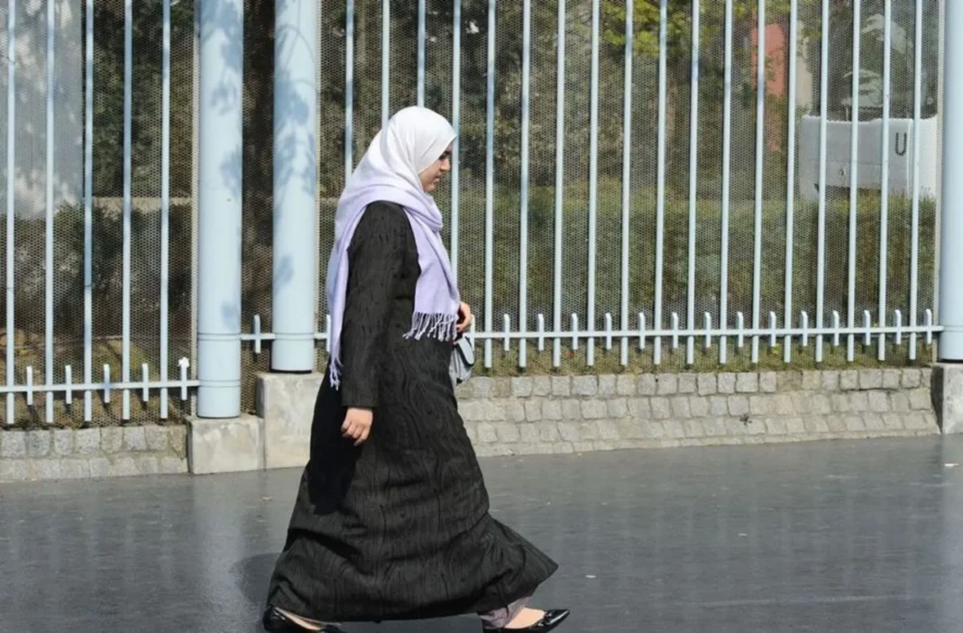 Enorme scandale! Le voile islamique est sur le point d’être banni en France. La Kippa, NON Femme en hijab marchant près d'une clôture en métal en France.