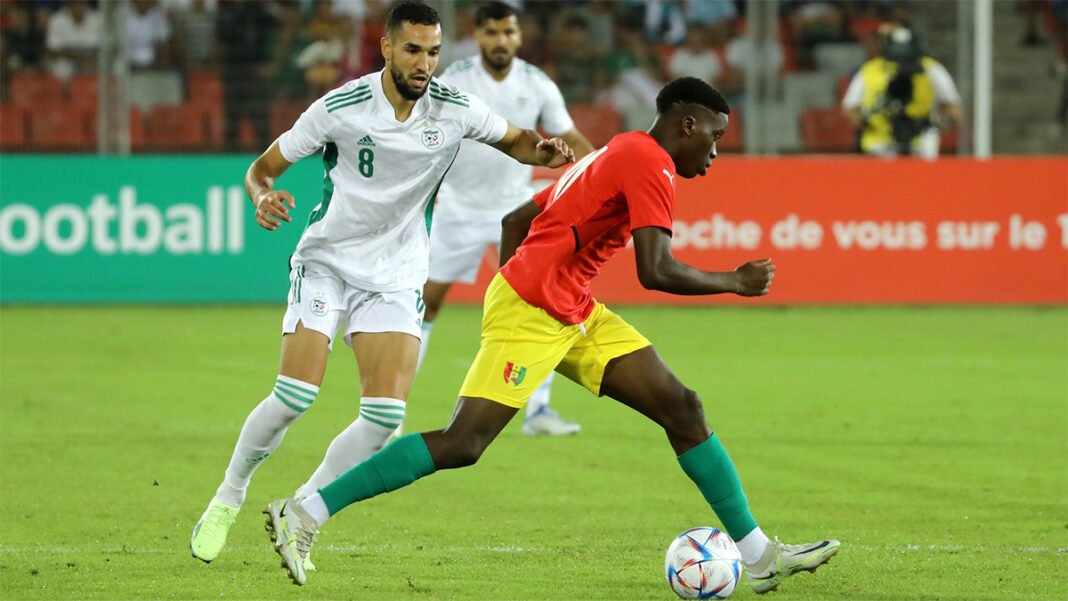 Qualif Coupe du monde 2026 : Algérie Maroc, la Guinée interpelle la CAF ! Joueur algérien en action contre un joueur marocain lors d'un match de football.