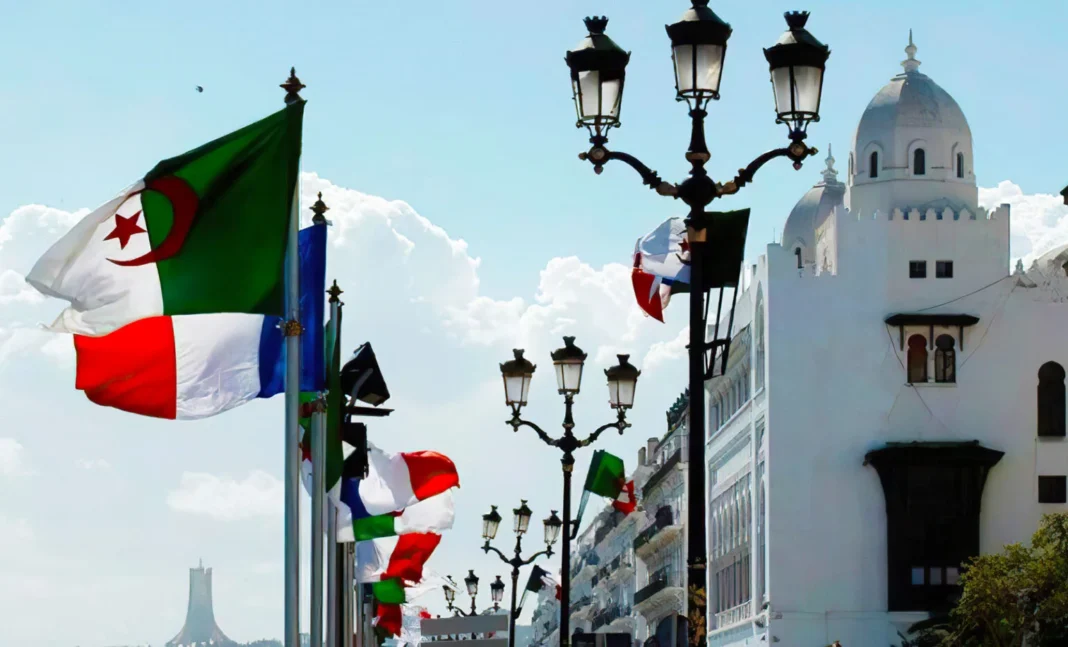 C’est très Faux! La France n’offre pas 800 millions d’euros annuellement à l’Algérie Drapeaux algérien et français flottant à Tunis avec architecture blanche.