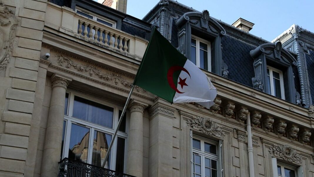 Drapeau algérien devant un bâtiment historique à Paris.
