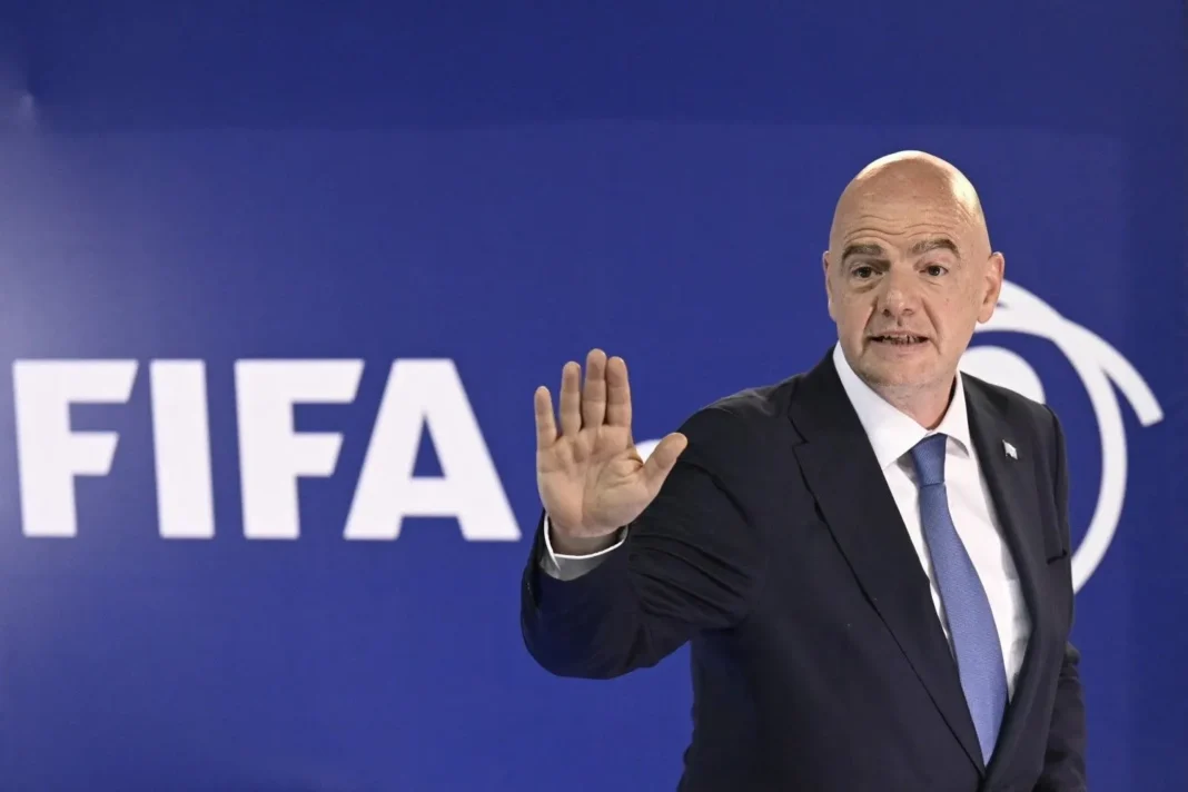 Personne en costume lors d'une conférence FIFA, faisant un geste de la main.