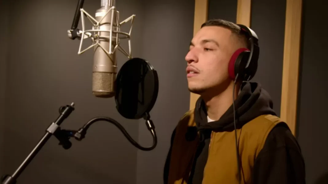 Youssef Swatt’s remporte la 3ᵉ saison de “Nouvelle École” sur Netflix : un triomphe mérité Youssef Swatt en studio, chantant dans un micro avec casque audio.