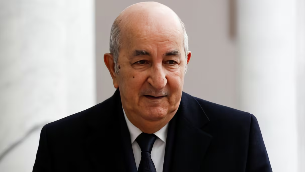 Homme politique algérien en réunion, visage sérieux, costume noir.