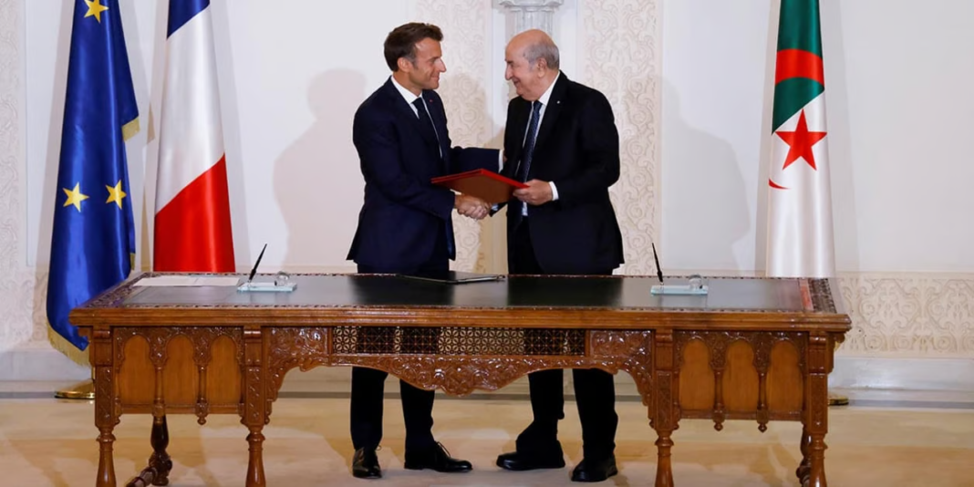 Deux hommes signent un accord officiel dans une salle élégante.