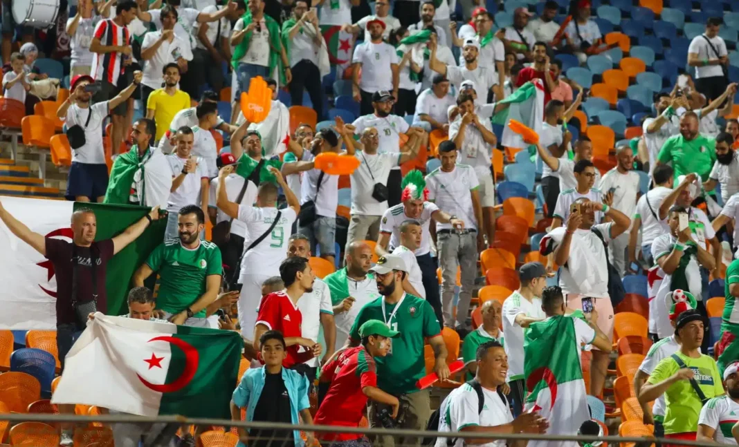 Tensions en Tunisie : Les fans du MC Alger dénoncent des prix de billets exorbitants Supporters algériens avec drapeaux et écharpes dans le stade.