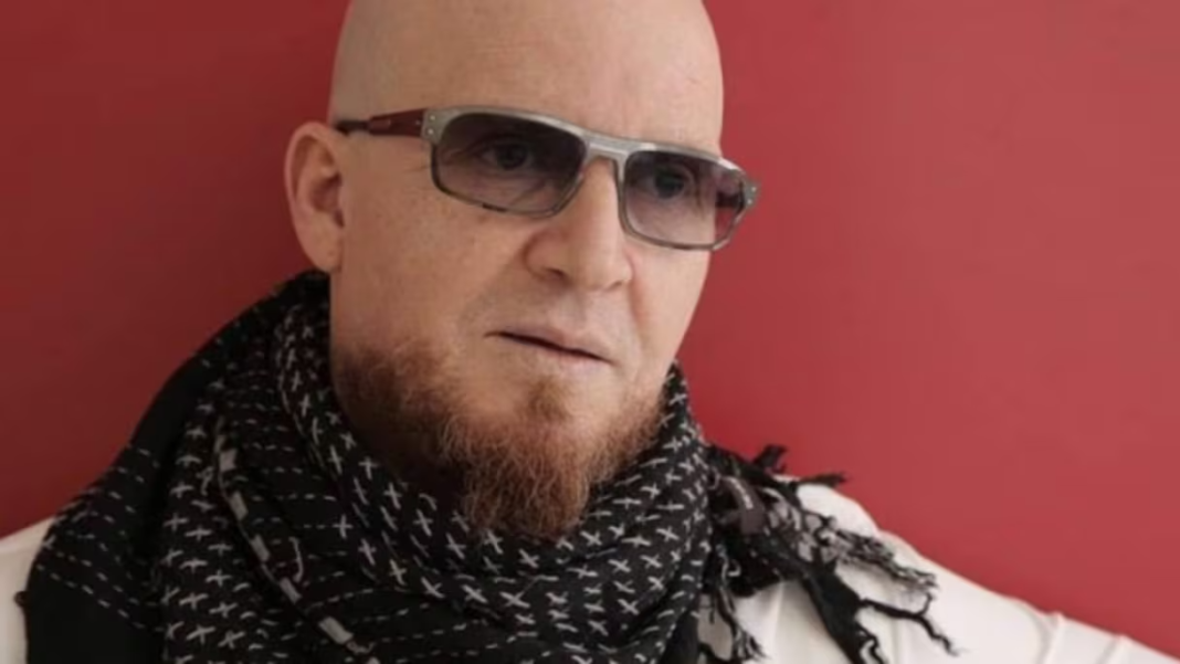 Cheb Bilal, chanteur de raï algérien, portant des lunettes et un foulard noir et blanc.