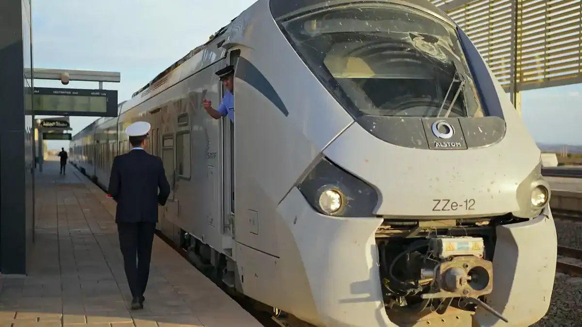 Train blanc moderne à la gare avec personnel en uniforme.