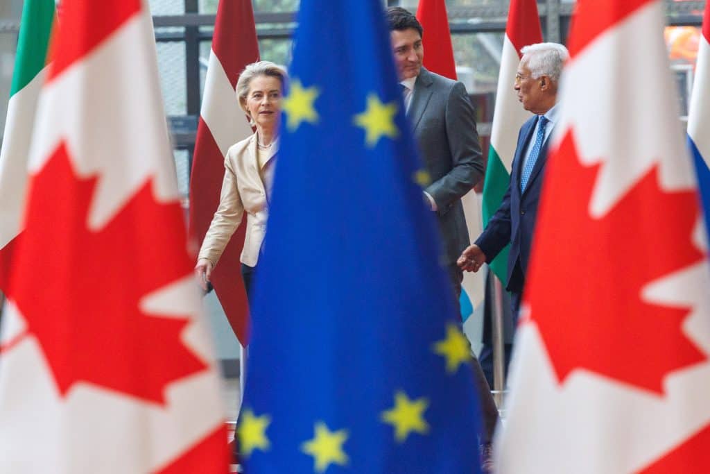 Migrations: Les femmes algériennes davantage vers l’étranger Rencontre entre dirigeants européens et canadiens avec drapeaux en arrière-plan.