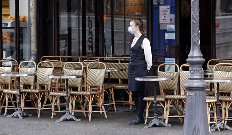 Restaurant halal de Lyon : une salle femmes fait débat Serveuse portant un masque dans un restaurant de Lyon avec des tables vides.