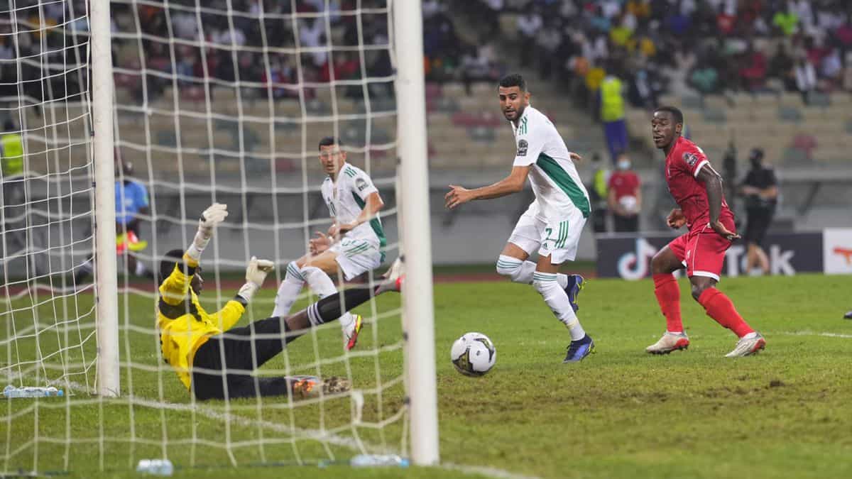 Joueur algérien tente de marquer face au gardien lors d'un match tendu.