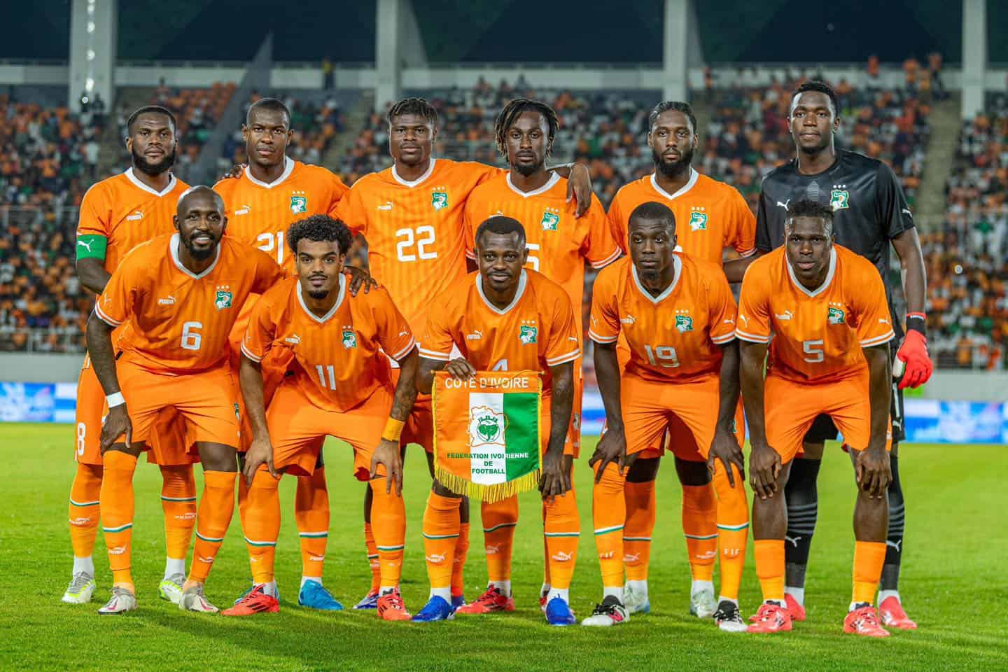 CAN 2025 : faux départ interdit pour les géants africains Groupe de joueurs de football africain en tenue orange sur le terrain.
