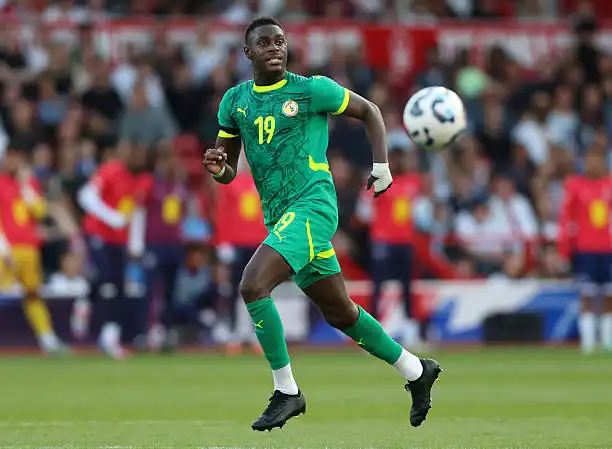 L’Algérie face à la malédiction : Le regard de Moussa Niakhaté Footballeur en mouvement portant le maillot vert de l'équipe nationale.
