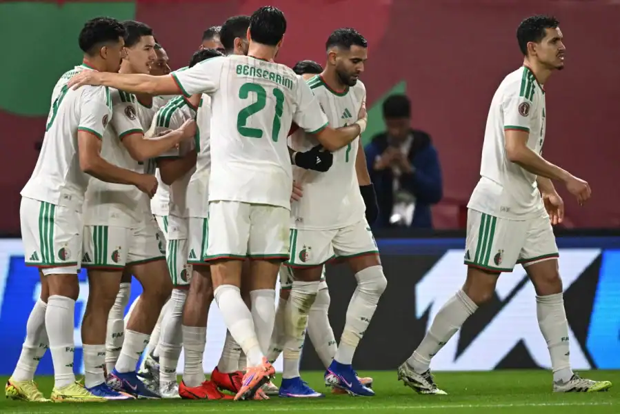 Équipe de football algérienne en célébration sur le terrain.