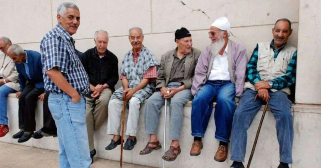 Hausse des retraites en Algérie : qui en profite vraiment ? Groupe de retraités algériens discutant et socialisant.