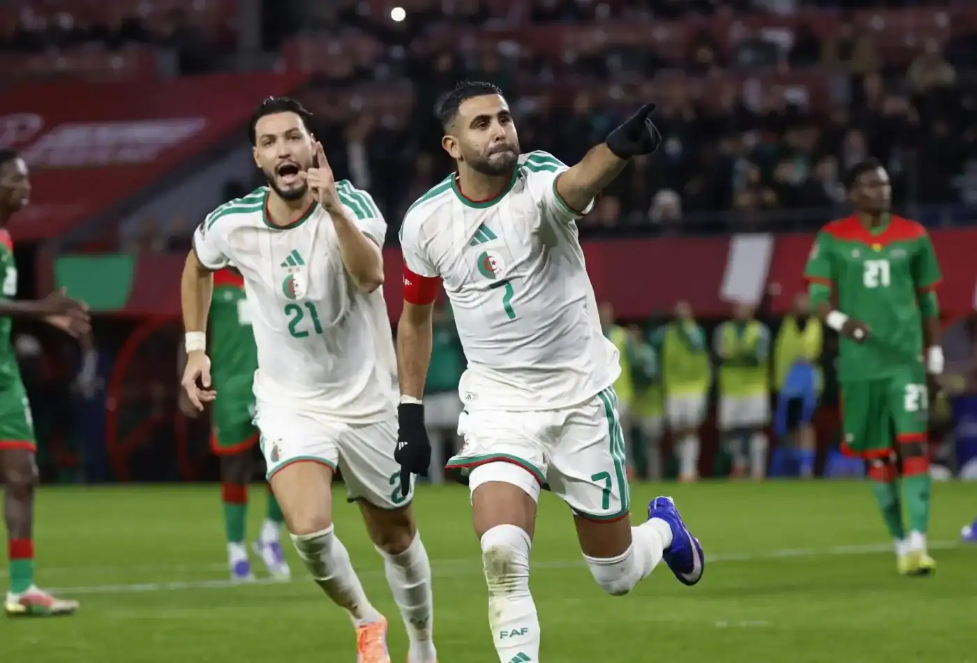 Joueurs algériens célébrant un but lors d'un match de football.