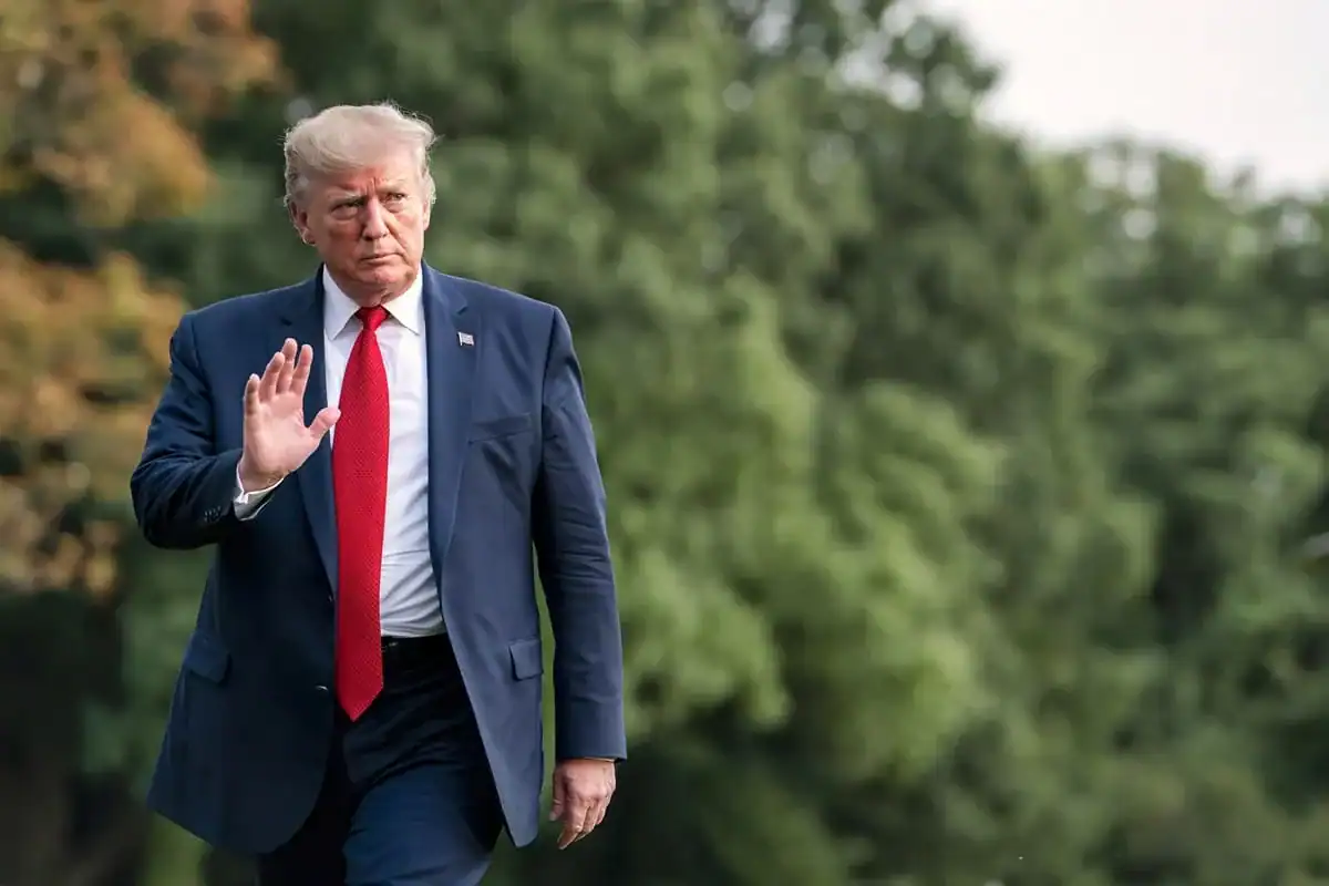 Washington envisage des frappes éclair contre l'Iran Donald Trump marchant dans un parc avec un geste de la main.