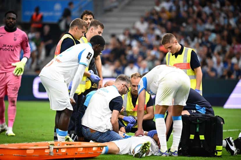 Joueur de football blessé sur le terrain entouré de médecins et de coéquipiers.