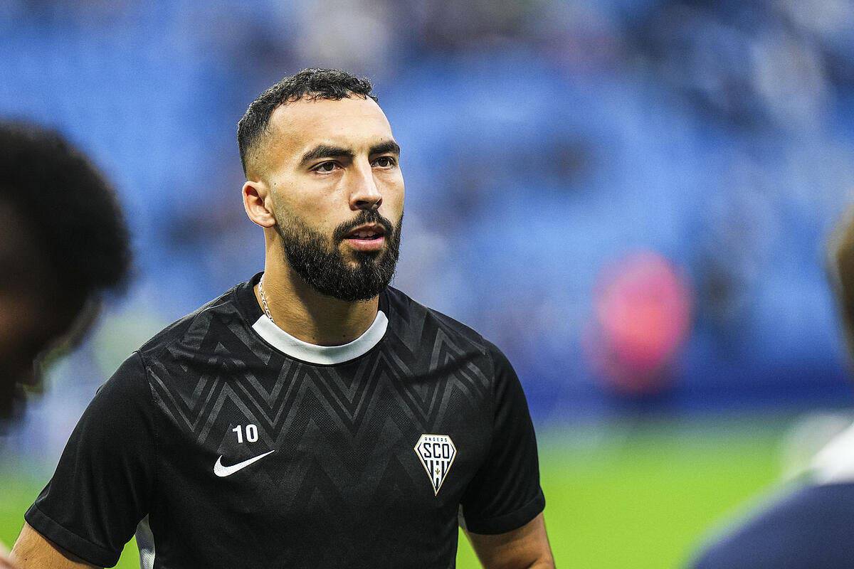 Pourquoi un joueur algérien est-il bloqué en France ? Joueur algérien portant maillot noir lors d'un match de football.