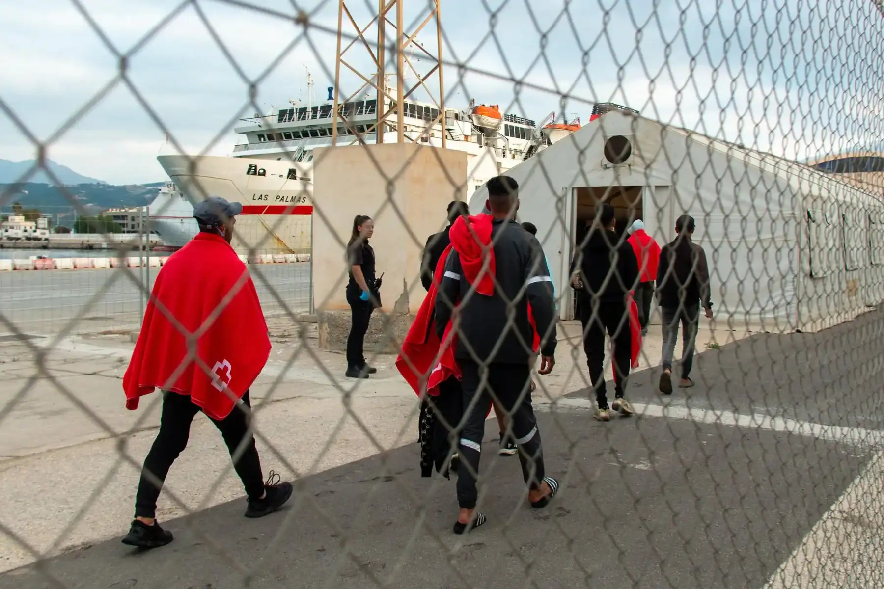 Migration clandestine par bateau Migrants traversant le port en direction d'un bateau de pêche.