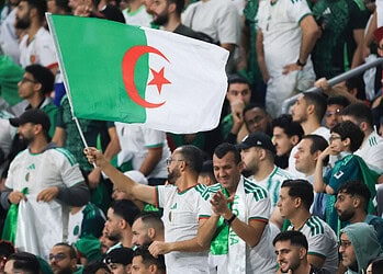 Fans algériens avec drapeau national lors de la match de football.