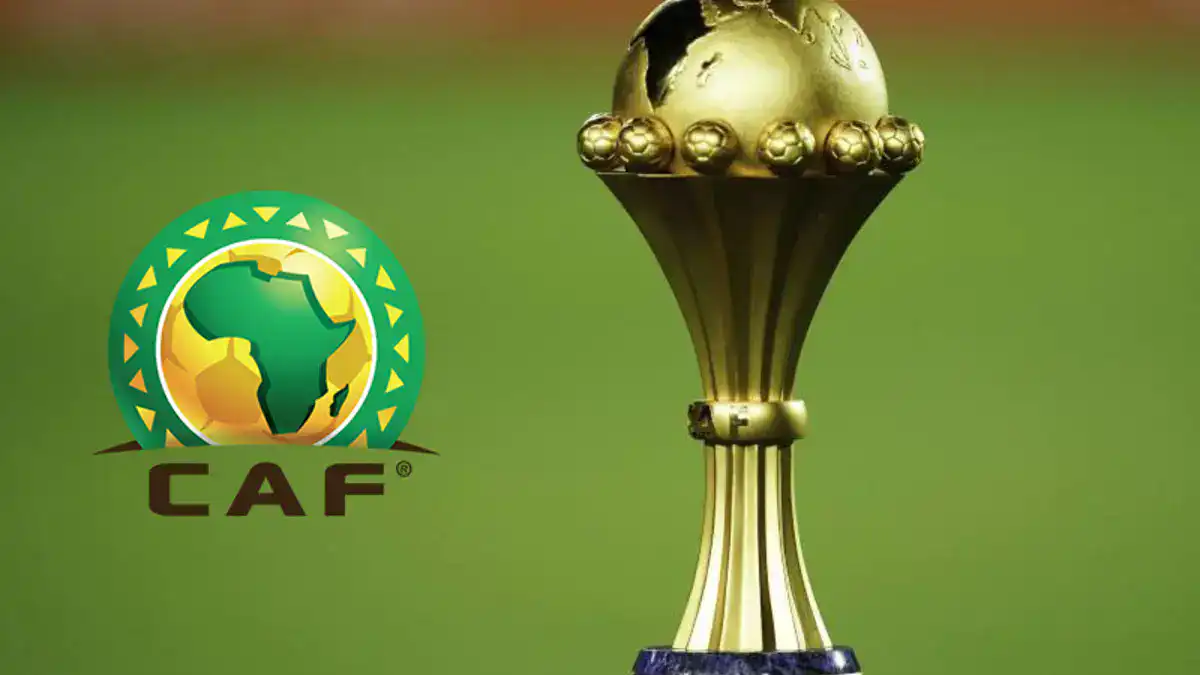 Trophée de la CAF en or sur fond vert de terrain de football.
