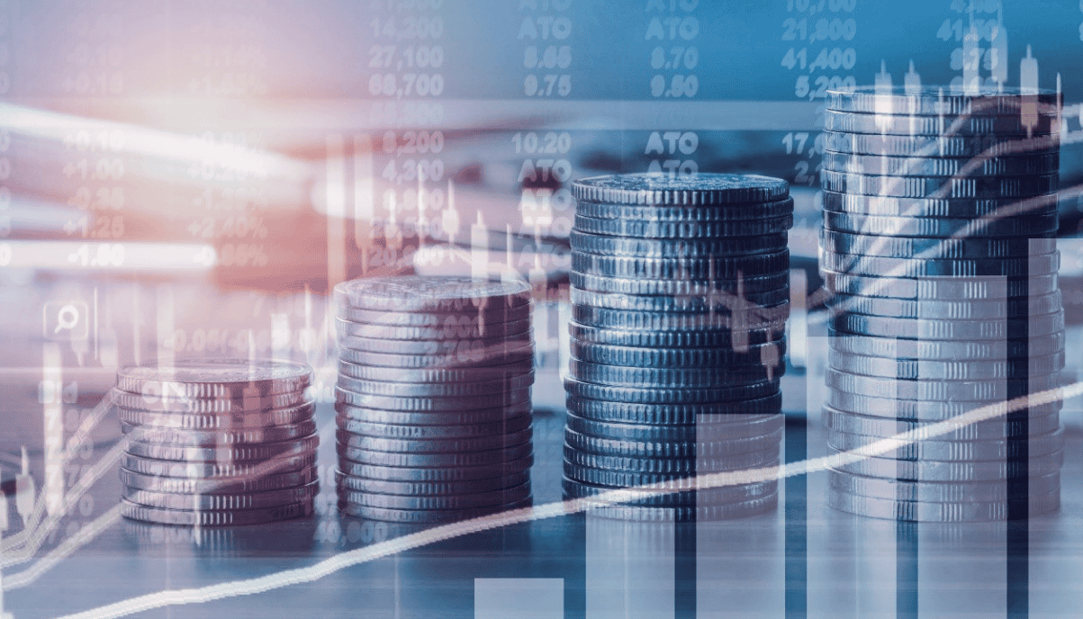 Stacks de pièces de monnaie avec graphiques financiers en arrière-plan.