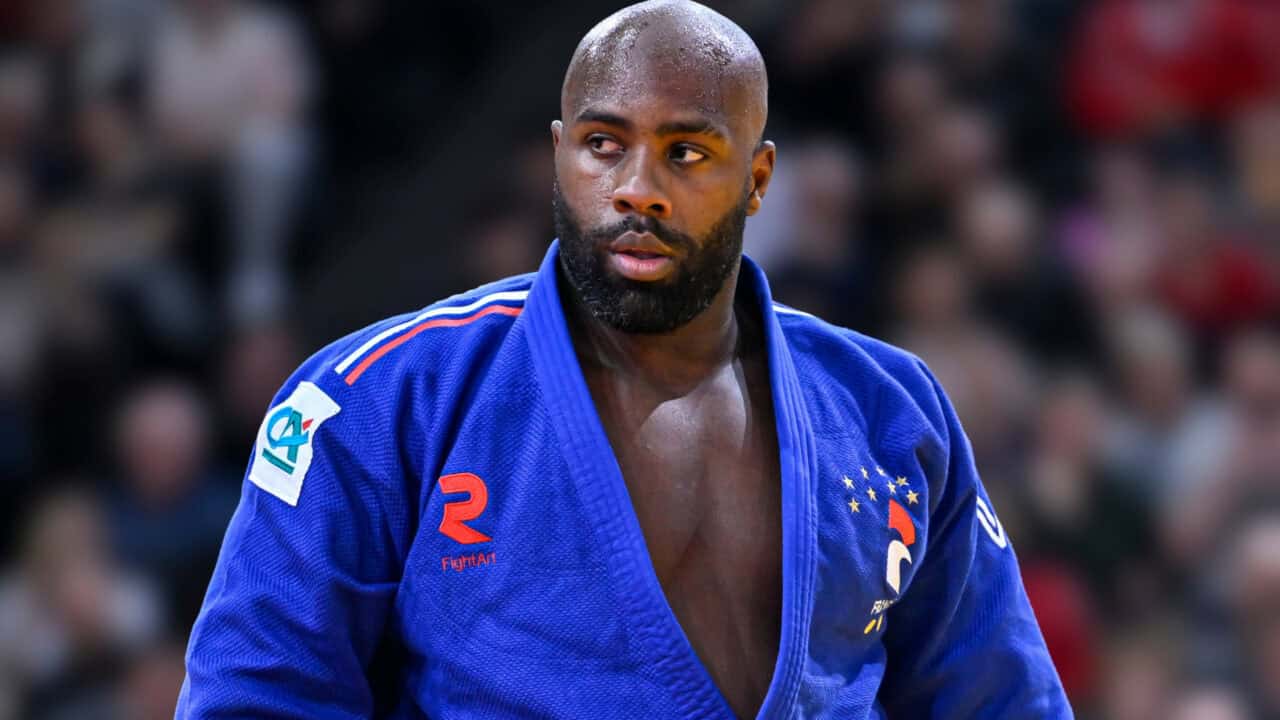 Athlète de judo en compétition portant un judogi bleu.