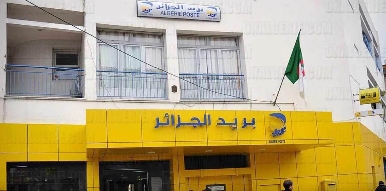 Algérie Poste alerte sur une nouvelle vague d’arnaques en ligne Bâtiment d'Algérie Poste avec drapeau national algérien.