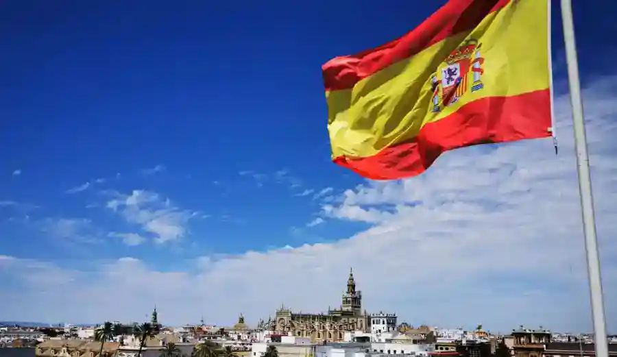Drapeau espagnol flottant au-dessus de la ville ensoleillée.