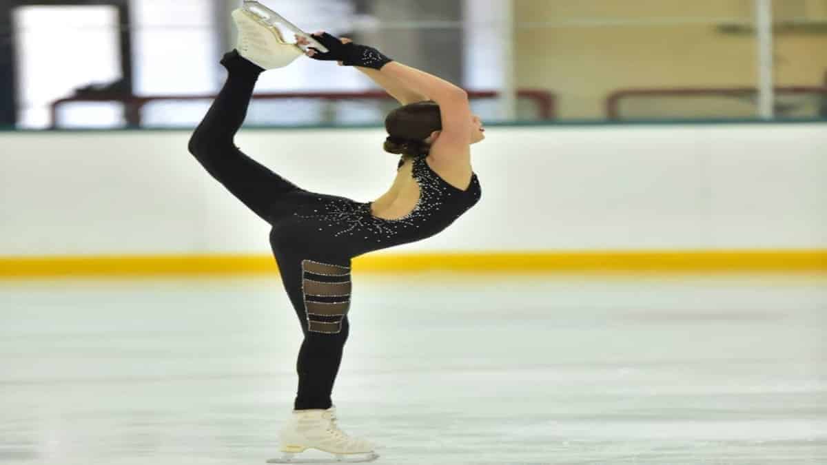 Jeune patineuse en position de figure artistique sur glace.