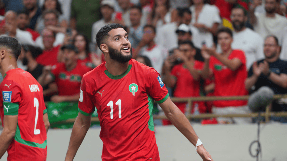 Saibari célèbre pour l'Algérie Saibari en action lors d'un match de football avec supporters en arrière-plan.