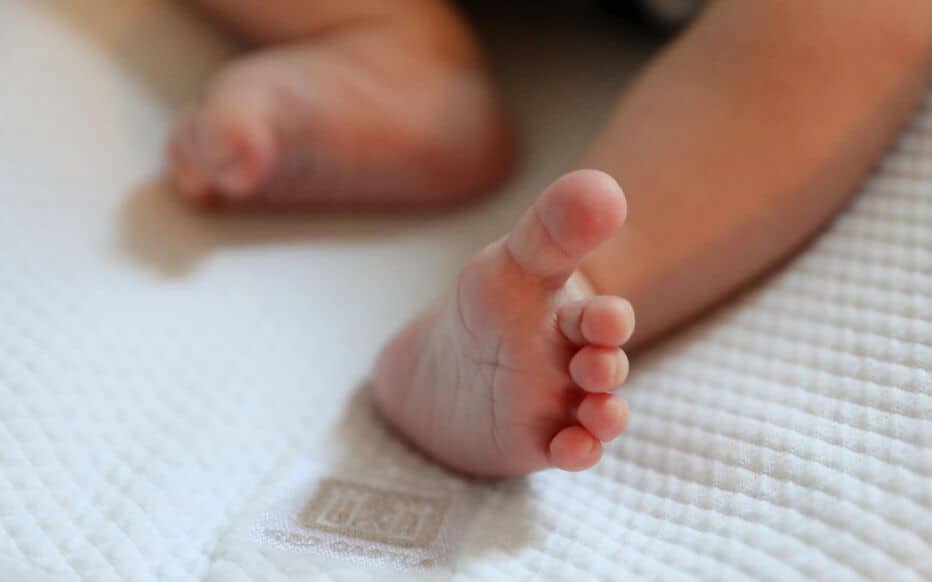 Bébé Zaïd : plainte des parents après des propos haineux Pied de bébé avec orteils, image douce et chaleureuse.
