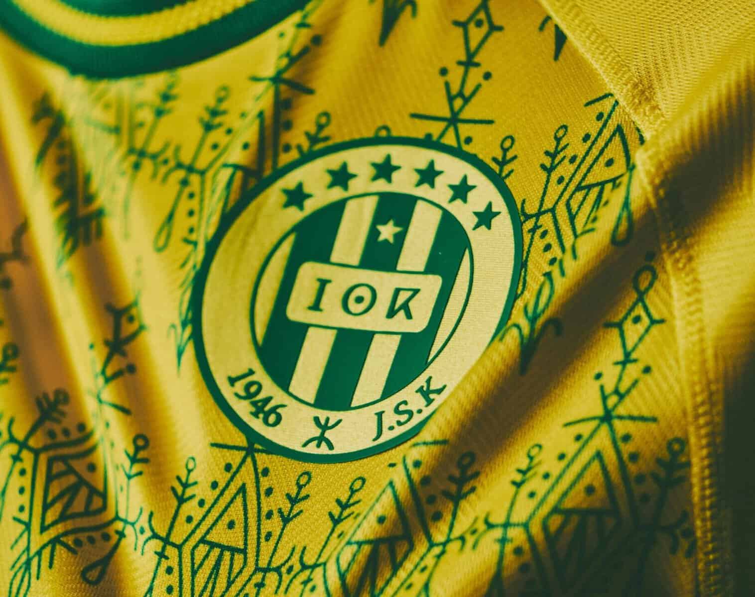 JSK : révélations sur l’argent bloqué et les grands projets Maillot jaune de l'équipe JSK avec logo et motifs décoratifs.