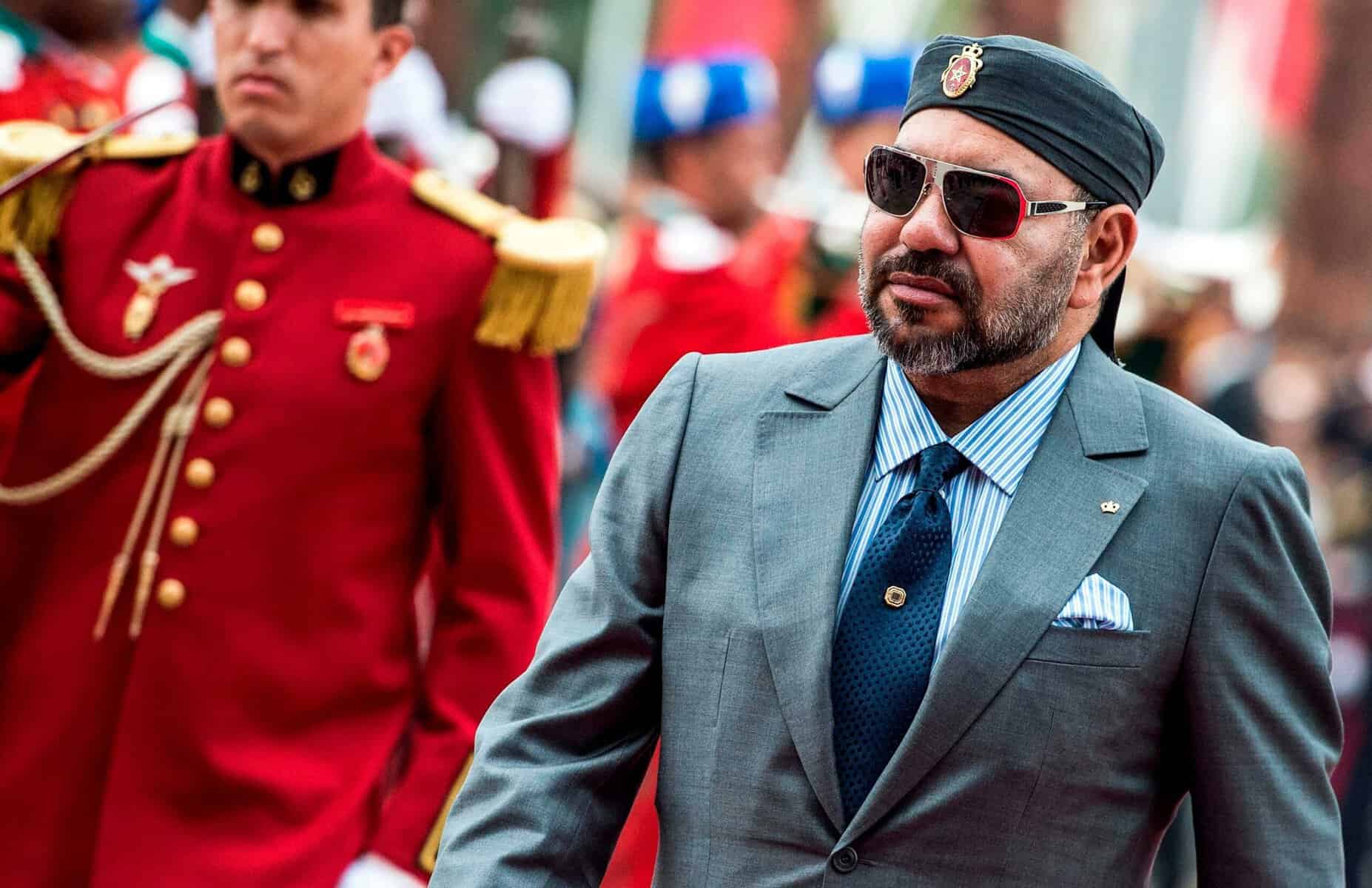Pauvreté au Maroc : en retard sur l’Algérie et la Tunisie Mohammed VI du Maroc avec lunettes de soleil et costume élégant.