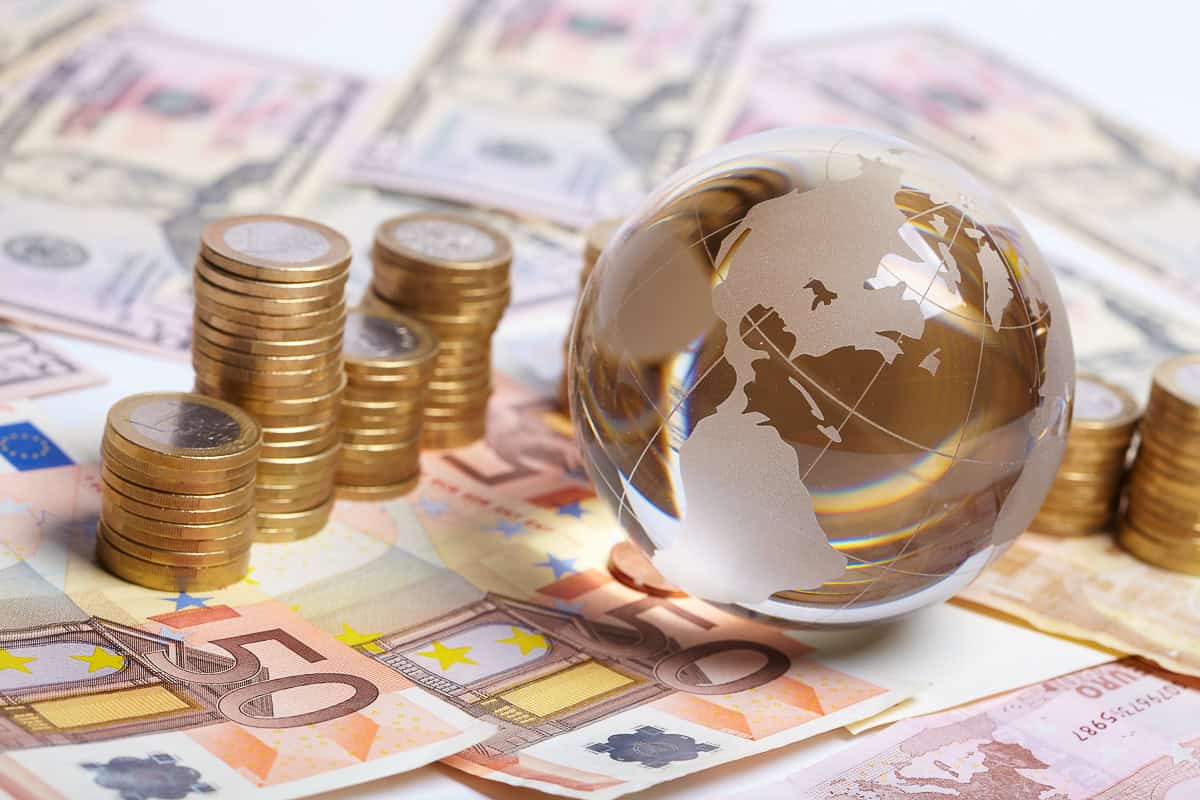 Restrictions sur les transferts de devises en Alg Monnaie et globe en verre illustrant les transferts de devises en Alg.