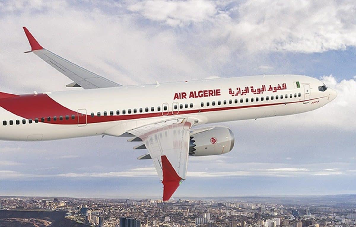 Avion Air Algérie en vol Avion Air Algérie survolant une ville avec ciel nuageux.