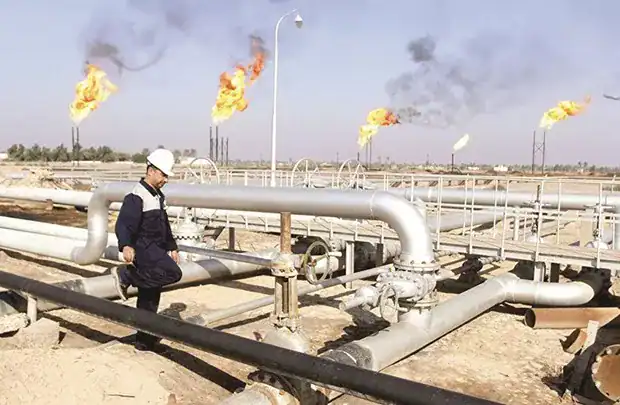 Puits de gaz avec flammes en flamme dans un site industriel en Algérie.