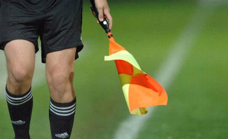 Arbitre de football tenant un drapeau sur le terrain.