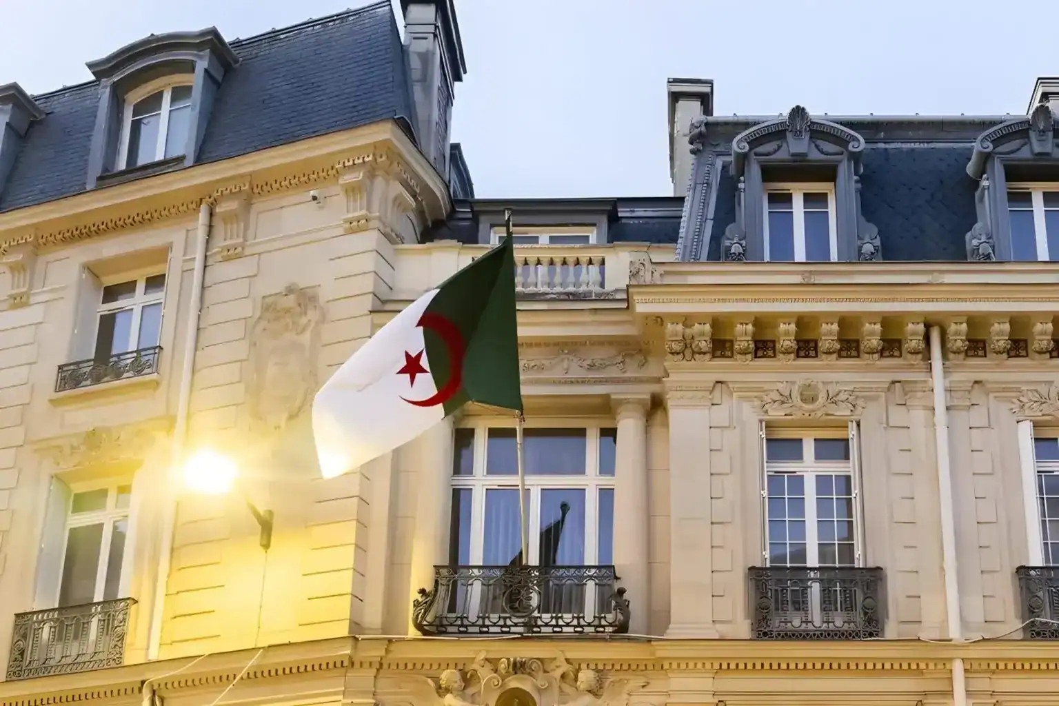 Une permanence consulaire algérienne exceptionnelle en France Drapeau algérien flottant devant un bâtiment parisien historique.