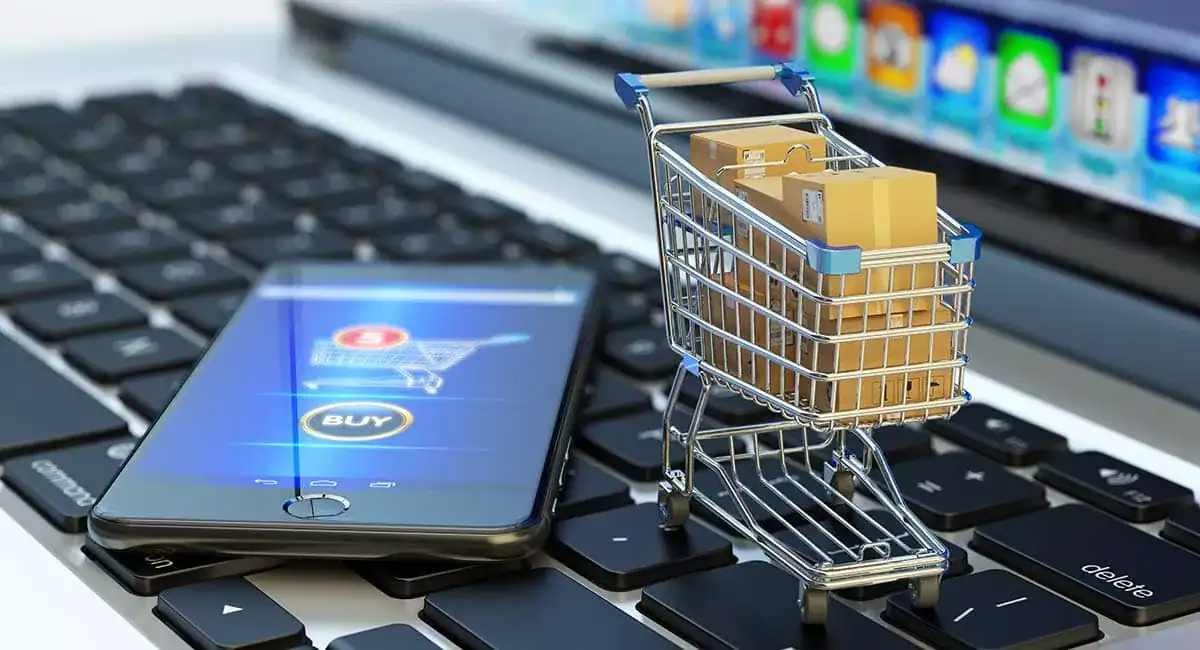 Algérie : un plan ambitieux pour équiper 1M de commerçants d’ici 2025 Panier de courses avec colis sur clavier d'ordinateur et smartphone.