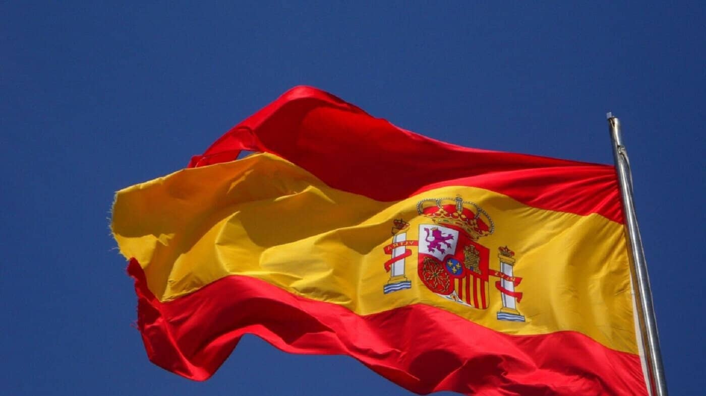 500 000 sans-papiers bientôt régularisés en Espagne ? Drapeau national espagnol flottant dans un ciel bleu clair.