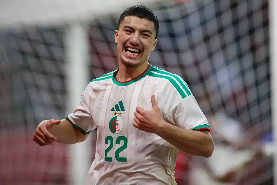 Maza interpelle Zerrouki : la scène qui fait débat Footballeur algérien souriant en maillot national.