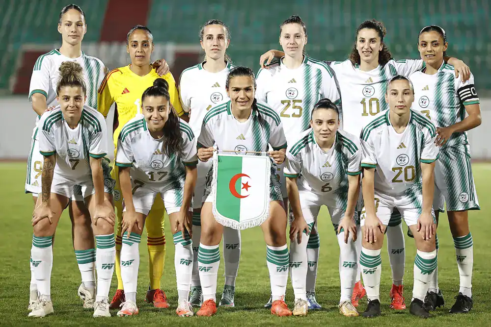 Groupe de joueuses de football algériennes avec drapeau national.