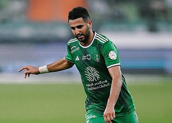 Riyad Mahrez en tenue verte sur le terrain de football.