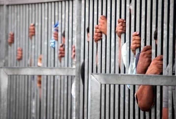 Détention en prison en Palestine Détention en prison avec des mains derrière les barreaux.